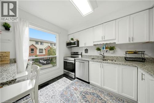 White kitchen cabinetry with stainless steel appliances, granite-style countertops, and a tile backsplash - 384 Limeridge Road E Unit# 16, Hamilton, ON 
