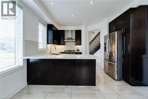 Kitchen featuring dark wood-finish cabinetry, stainless steel appliances, a center island with a sink, recessed lighting, and light-toned floor tiling - 2 Hawstone Road, Vellore, ON 