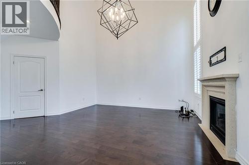 Wood-finish flooring, high ceilings, contemporary chandelier, stone fireplace surround, and plantation shutters - 2 Hawstone Road, Vellore, ON 