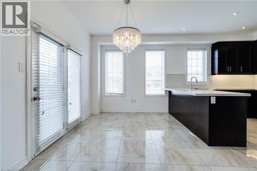 Kitchen area with an island featuring a built-in sink, dark cabinetry, and light countertops - 2 Hawstone Road, Vellore, ON 