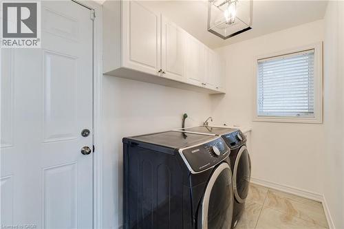 Laundry area featuring upper cabinetry, a utility sink, and tile flooring - 2 Hawstone Road, Vellore, ON 