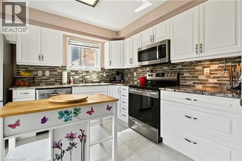 White cabinetry with stainless steel appliances, stone countertops, and a tiled backsplash - 31 Grindstone Way, Hamilton, ON 