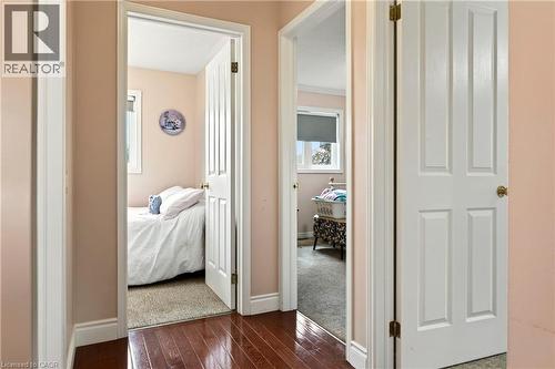 Hardwood-finish flooring extending into two separate doorways, each opening into a distinct room with carpeted flooring - 31 Grindstone Way, Hamilton, ON 
