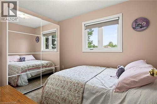 Mirrored wardrobe with multiple panels, large window with roller shade, and ceiling-mounted light fixture - 31 Grindstone Way, Hamilton, ON 
