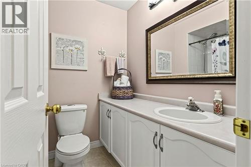 Vanity with integrated sink, white cabinet storage, and an ornate framed mirror - 31 Grindstone Way, Hamilton, ON 