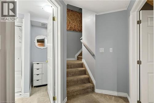 Carpeted staircase with white handrail and baseboards, leading to a textured wall accent - 31 Grindstone Way, Hamilton, ON 