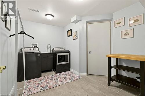 Laundry area featuring tile flooring, built-in cabinetry with a sink, and a flush-mount ceiling light - 31 Grindstone Way, Hamilton, ON 