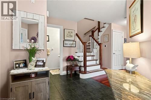 Two-tone staircase with wood handrails, dark tile flooring, and wood-finish flooring - 31 Grindstone Way, Hamilton, ON 