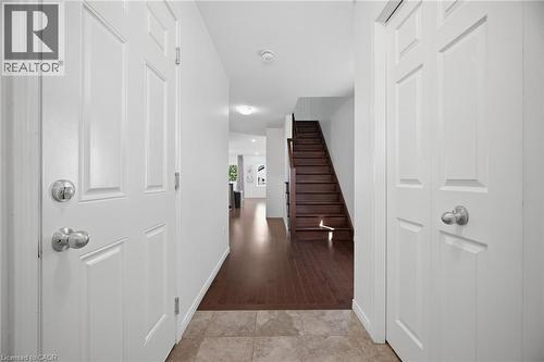 Entryway featuring light-toned tile flooring, white paneled doors with chrome hardware, wood-finish flooring extending into interior spaces, and a dark wood staircase - 135 Hardcastle Drive Unit# 85, Cambridge, ON 