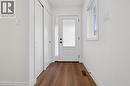 Entryway featuring wood-finish flooring, a white paneled door with glass insert, a side window, and two white bi-fold closet doors - 2294 Seton Crescent, Burlington, ON 