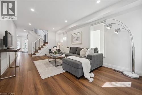 Hardwood-finish flooring, recessed lighting, white walls, white trim, and a staircase with white risers and dark wood treads - 2294 Seton Crescent, Burlington, ON 