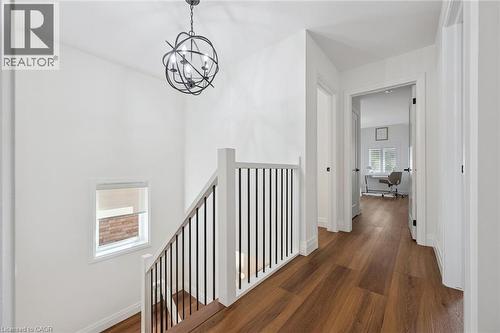 Wood-finish flooring, contemporary chandelier, white walls, and dark hardware - 2294 Seton Crescent, Burlington, ON 