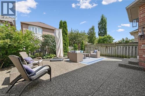 Expansive patio with exposed aggregate surface, mature perimeter landscaping, and a privacy fence - 2294 Seton Crescent, Burlington, ON 