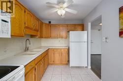 Kitchen featuring wood cabinetry, white countertops, a dual basin sink with a gooseneck faucet, and tile flooring - 