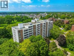 Multi-story building featuring balconies, surrounded by mature trees and landscaped grounds - 