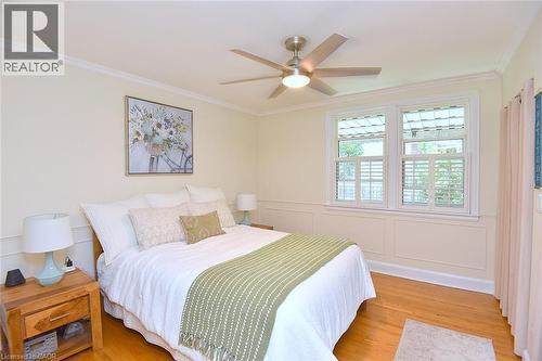 Hardwood flooring, crown molding, white wainscoting, and a ceiling fan with integrated lighting - 936 Boothman Avenue, Burlington, ON 