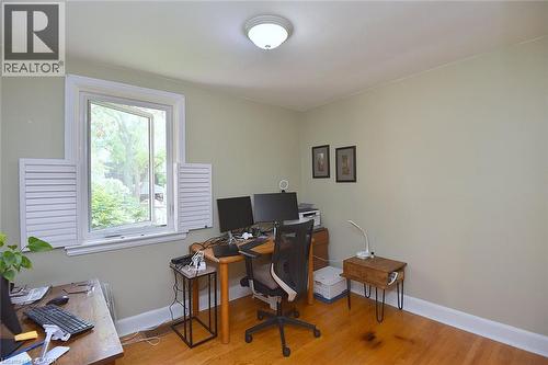 Hardwood flooring, light-toned walls, white trim, window with white louvered shutters, and a flush-mount ceiling light fixture - 936 Boothman Avenue, Burlington, ON 