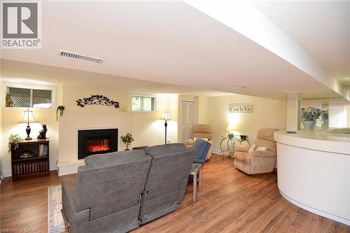 Recessed ceiling, wood-finish flooring, built-in electric fireplace, curved built-in bar, and multiple windows - 936 Boothman Avenue, Burlington, ON 