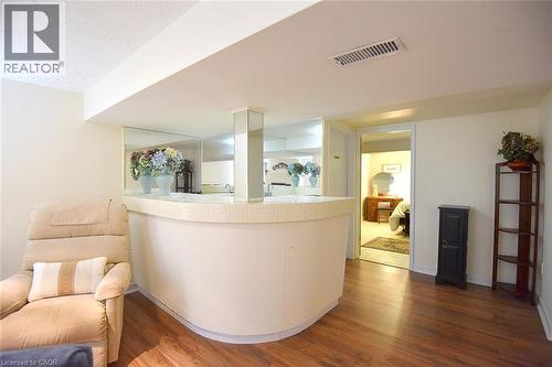 Built-in curved bar with a tiled counter, mirrored backsplash, and wood-finish flooring - 936 Boothman Avenue, Burlington, ON 
