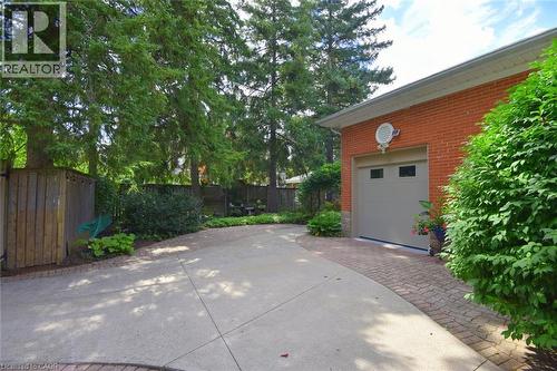 Brick exterior garage with a light-colored garage door featuring windows, bordered by a paver driveway accent - 936 Boothman Avenue, Burlington, ON 
