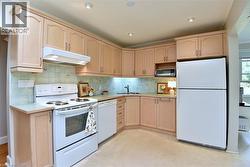 Kitchen featuring light wood cabinetry, recessed lighting, and a tile backsplash - 