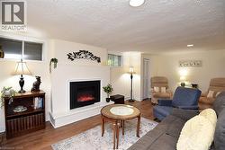 Recessed lighting, wood-finish flooring, white walls, and a fireplace with a mantel - 