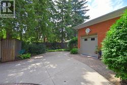 Brick exterior garage with a light-colored garage door featuring windows, bordered by a paver driveway accent - 