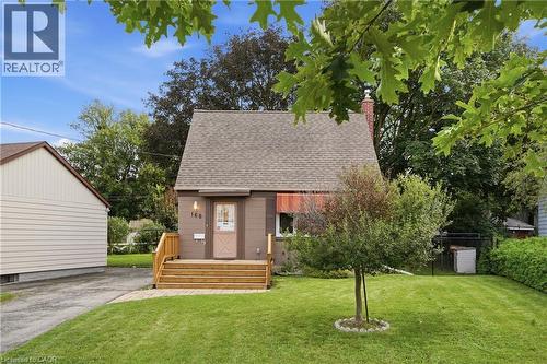 Gable roofline, exterior siding in a neutral tone, front entry with wood steps, mature front yard landscaping, and paved driveway - 160 Lorne Crescent, Kitchener, ON 