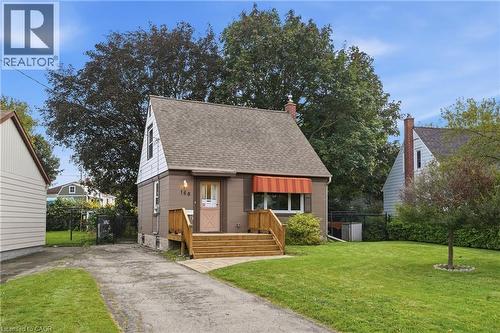 Gabled roofline, front entry with wood steps, red and white striped window awning, paved driveway, and established green lawn - 160 Lorne Crescent, Kitchener, ON 