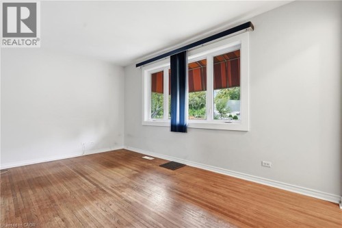 Light-filled room featuring wood-finish flooring, white walls, and a multi-pane window with white trim - 160 Lorne Crescent, Kitchener, ON 