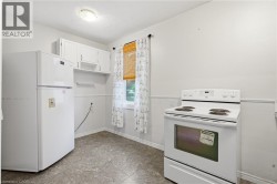 White kitchen appliances, upper cabinetry, a single window, overhead lighting, and resilient flooring - 