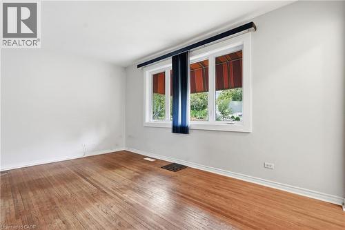 Light-filled room featuring wood-finish flooring, white walls, and a multi-pane window with white trim - 160 Lorne Crescent, Kitchener, ON 