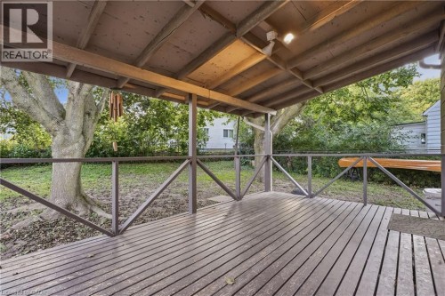 Covered wood deck with wooden railings, exposed wood beam ceiling, and overhead lighting - 160 Lorne Crescent, Kitchener, ON 
