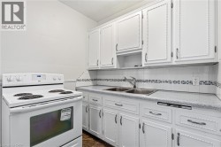 Kitchen featuring white upper and lower cabinetry, a built-in double basin sink, and a white electric range - 