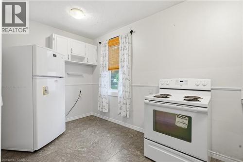 White kitchen appliances, upper cabinetry, a single window, overhead lighting, and resilient flooring - 160 Lorne Crescent, Kitchener, ON 