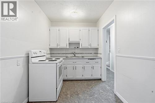 White upper and lower cabinetry with chrome hardware, an integrated sink, a built-in dishwasher, and a white electric range - 160 Lorne Crescent, Kitchener, ON 