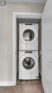 Stackable washer and dryer within a dedicated closet, featuring a front-loading design and panel controls - 