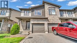 Brick and siding exterior with dark trim, featuring a paver driveway, an attached single-car garage, and a covered entry - 