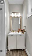 Vanity with integrated sink, gold-framed mirror, three-light vanity fixture, and wood-finish flooring - 