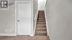Carpeted staircase with white handrail, leading to an upper level - 