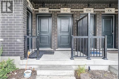 Brick exterior with multiple panel doors and individual unit numbering - 102 Wheat Lane, Kitchener, ON 