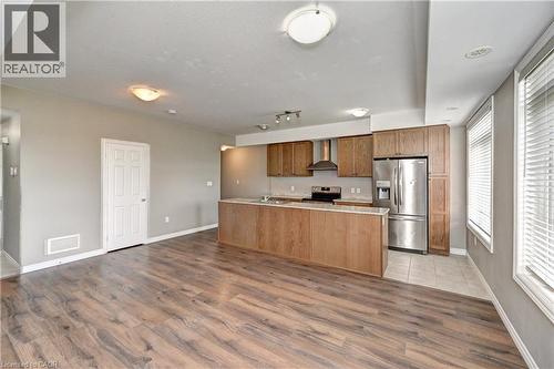 Wood-finish flooring, recessed lighting, wood cabinetry, stainless steel appliances, and a kitchen island - 102 Wheat Lane, Kitchener, ON 