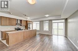 Open-concept kitchen with wood-finish cabinetry, stainless steel appliances, and an expansive island - 