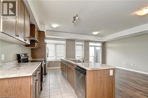 Kitchen featuring wood-finish cabinetry, stainless steel appliances, and a central island with a double sink - 102 Wheat Lane, Kitchener, ON 