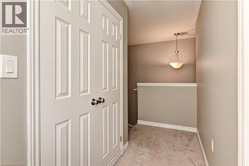 White paneled bifold doors, neutral tone walls, and recessed carpet flooring - 102 Wheat Lane, Kitchener, ON 