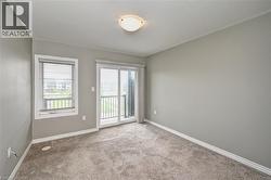 Plush carpet flooring, neutral wall tones, crown molding, and a sliding glass door leading to a balcony - 