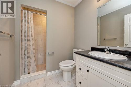 Tiled shower enclosure, white vanity with black countertop, integrated sink, large wall mirror, and white tile flooring - 102 Wheat Lane, Kitchener, ON 