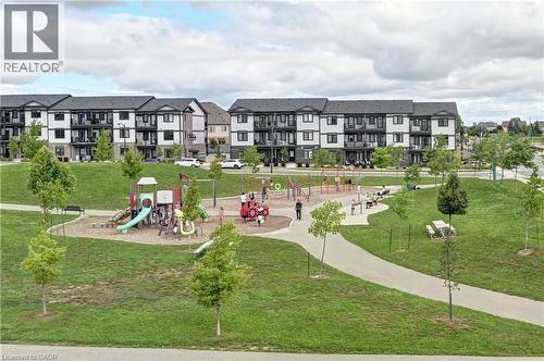 Modern residential community featuring expansive green spaces with mature landscaping, multiple playgrounds with colorful equipment, paved pathways, and contemporary multi-story apartment buildings wi - 102 Wheat Lane, Kitchener, ON 