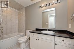 Bathroom with tiled flooring, white vanity, dark countertop, and integrated sink - 