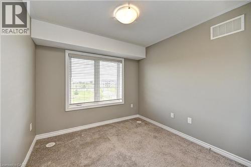 Wall-to-wall carpeting, neutral wall color, white trim, and a window with blinds - 102 Wheat Lane, Kitchener, ON 